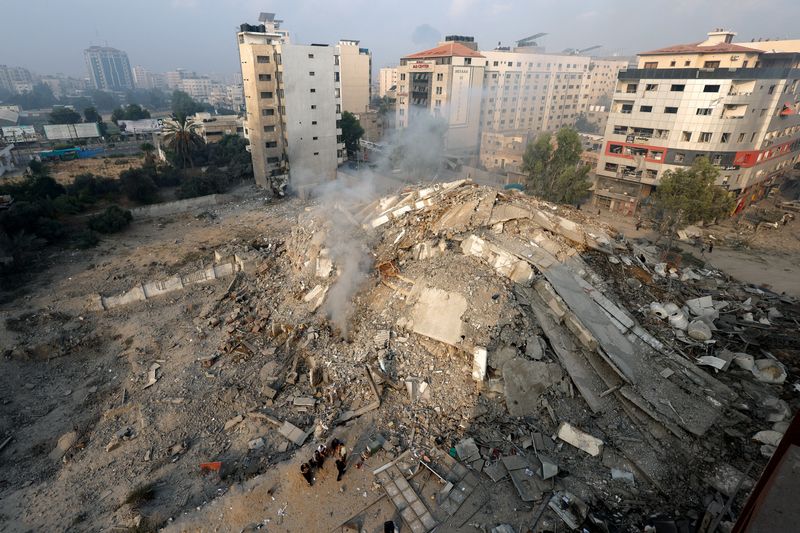 &copy; Reuters. فلسطينيون بتفقدون حطام برج الوطن الذي دُمر في قصف إسرائيلي بمدينة غزة يوم الأحد. تصوير: محمد سالم - رويترز.