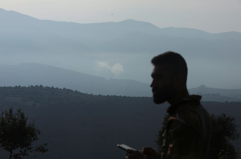© Reuters. رجل يقف في قرية إبل السقي فيما يتصاعد الدخان في حلتا جنوب لبنان يوم الأحد. تصوير: عزيز طاهر - رويترز.