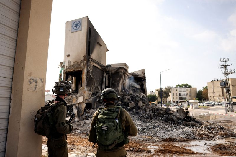&copy; Reuters. جنود إسرائيليون ينظرون إلى بقايا مركز شرطة في سديروت بجنوب إسرائيل يوم الأحد. تصوير: رونين زفولون - رويترز.
