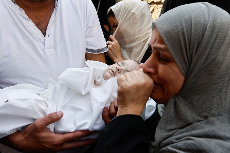 &copy; Reuters. Palestinos seguram corpo de bebê de gêmeos palestinos Ossayd e Mohammad Abu Hmaid, que autoridades de saúde disseram que foi morto junto com sua mãe e três irmãs em ataques israelenses.
REUTERS/Ibraheem Abu Mustafa