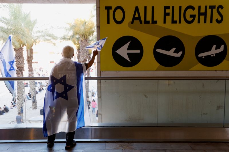 &copy; Reuters. FILE PHOTO: A person waves an Israeli flag as people demonstrate in response to Israeli Prime Minister Benjamin Netanyahu and his nationalist coalition government's judicial overhaul, at Ben Gurion International Airport in Lod, Israel July 11, 2023. REUTE