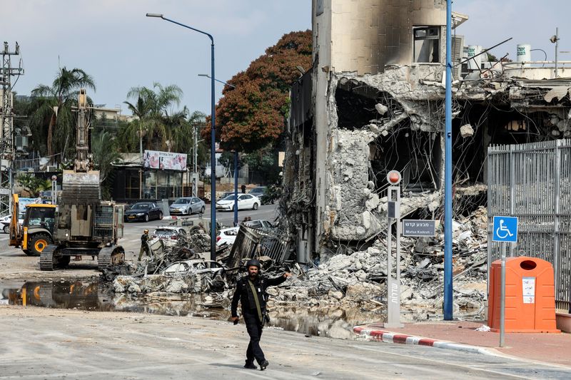 &copy; Reuters. أحد أفراد القوات الإسرائيلية يسير أمام مركز للشرطة الإسرائيلية يوم الأحد في سيدروت والذي شهد معركة مع مسلحي حركة حماس عقب تسللهم إلى المدين