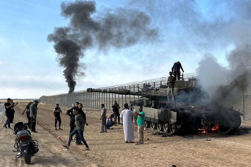 &copy; Reuters. فلسطينيون يتفقدون دبابة إسرائيلية محترقة على الجانب الإسرائيلي من الحدود مع قطاع غزة عقب تعرضها لهجوم شنه مسلحون فلسطينيون تسللوا إلى جنوب