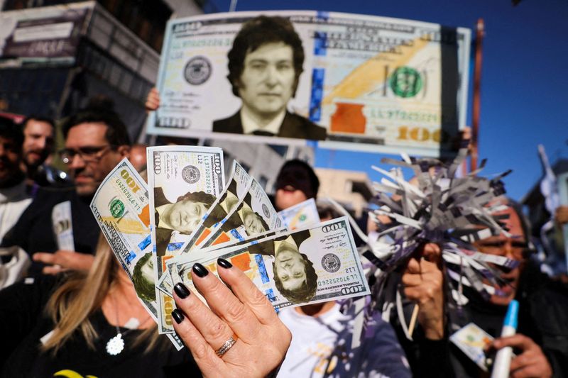 © Reuters. FILE PHOTO: Supporters of Argentine presidential candidate Javier Milei hold dollar bills with his face on them, during a campaign rally, in Buenos Aires, Argentina September 25, 2023. REUTERS/Cristina Sille//File Photo