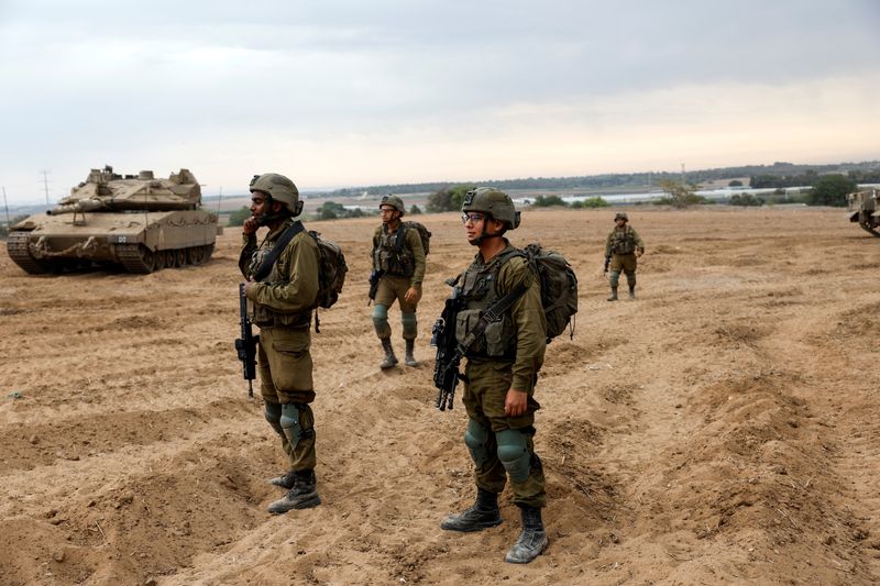 &copy; Reuters. جنود إسرائيليون ينظرون إلى منطقة تتجمع فيها الدبابات ومركبات الميليشيات الإسرائيلية على الجانب الإسرائيلي من حدود غزة يوم الاثنين. تصوير: 
