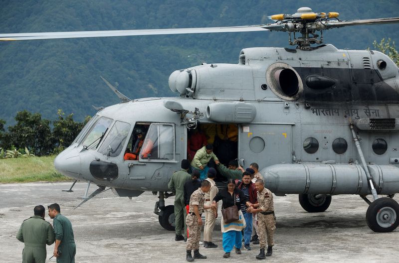 © Reuters. Central Reserve Police Force personnel help people disembark from an Indian Air Force helicopter after they were rescued from Lachen, an inaccessible area due to flash floods caused by a lake burst, at Mangan Helipad in Sikkim, India, October 9, 2023. REUTERS/Francis Mascarenhas