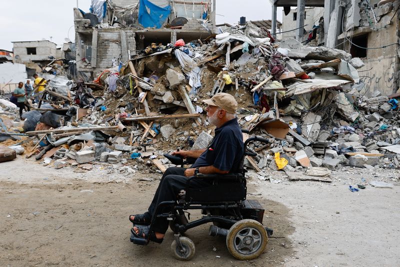 © Reuters. A Palestinian on a wheelchair passes by ruins of buildings destroyed in Israeli strikes, in Rafah in the southern Gaza Strip October 9, 2023. REUTERS/Ibraheem Abu Mustafa