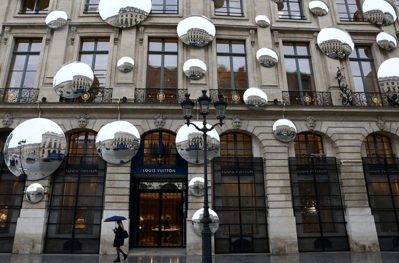 © Reuters. A woman under an umbrella walks past the luxury retailer Louis Vuitton store at Place Vendome in Paris, France, March 22, 2023. REUTERS/Yves Herman/File photo