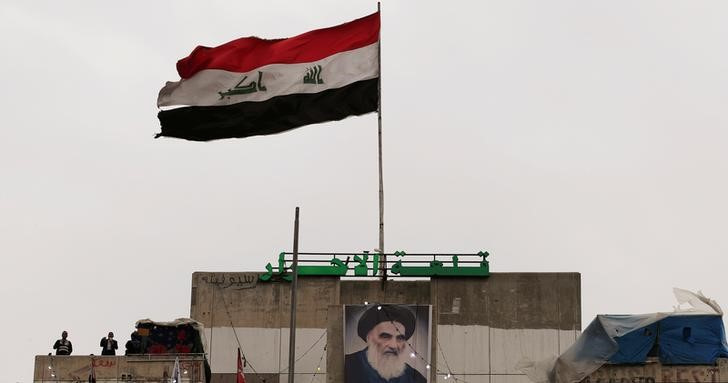 &copy; Reuters. Foto de archivo de un poster del principal clérigo chií de Irak, el gran ayatolá Ali al-Sistani, junto a una bandera iraquí en Bagdad
Febr 9, 2020. REUTERS/Thaier al-Sudani