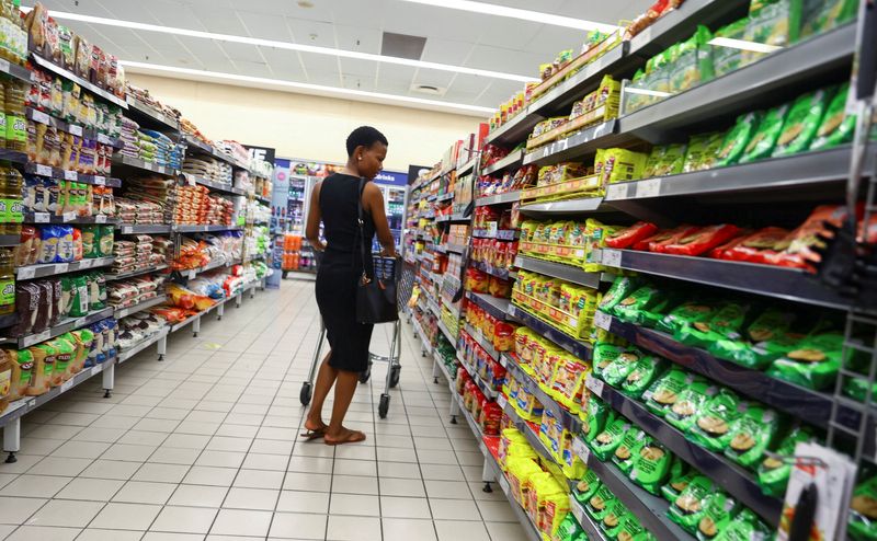 &copy; Reuters. FILE PHOTO: A customer compares prices while shopping at a Pick and Pay shop in East London, in the Eastern Cape province, South Africa, March 17, 2023. REUTERS/Siphiwe Sibeko/File Photo