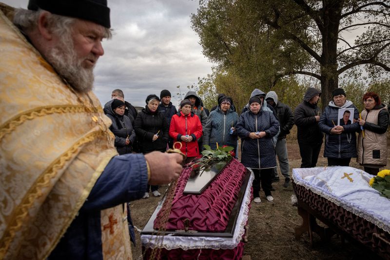 &copy; Reuters. FILE PHOTO: Family and relatives attend the funeral of Iryna Kharbaka and Oleksandr Khodak who were killed in a Russian missile attack, amid Russia's ongoing invasion of Ukraine, at the village cemetery, in the village of Hroza, near Kharkiv, Ukraine Octo