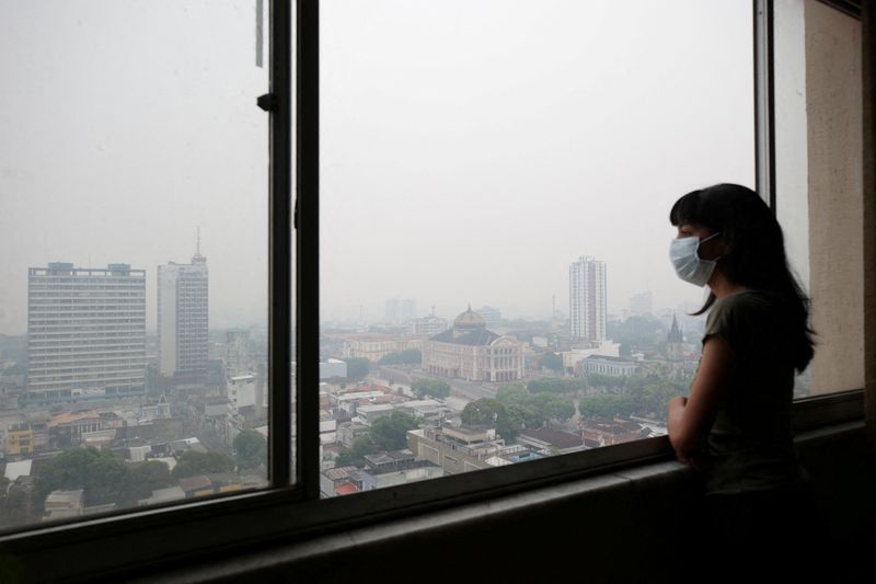 &copy; Reuters. La periodista Indiara Bessa mira desde su apartamento mientras se ve el humo de los incendios forestales en el Amazonas en Manaos, Brasil. 12 de octubre de 2023. REUTERS/Bruno Kelly