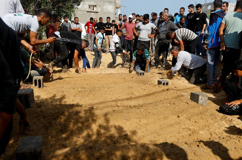 &copy; Reuters. أشخاص ينضحون الماء عقب قيامهم بدفن جثامين أفراد من عائلة فلسطينية قتلوا جراء ضربات إسرائيلية على منزلهم في خان يونس بجنوب قطاع غزة يوم الخم