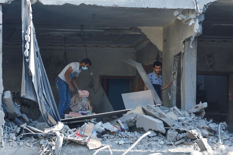 &copy; Reuters. Civili palestinesi cercano vititme nei resti di un palazzo dopo i bombardamenti delle forze israeliane. Khan Younis, Striscia di Gaza. 13 ottobre 2023. REUTERS/Ibraheem Abu Mustafa