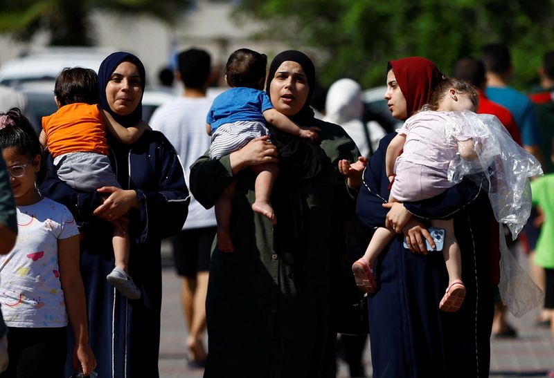 © Reuters. Families of staff of international organizations shelter at a United Nations center after UNRWA said it relocated its central operations centre to the south of Gaza Strip after Israel's call for more than 1 million civilians in northern Gaza to move south within 24 hours, amid the Israeli-Palestinian conflict, in Khan Younis in the southern Gaza Strip October 13, 2023.  REUTERS/Ibraheem Abu Mustafa