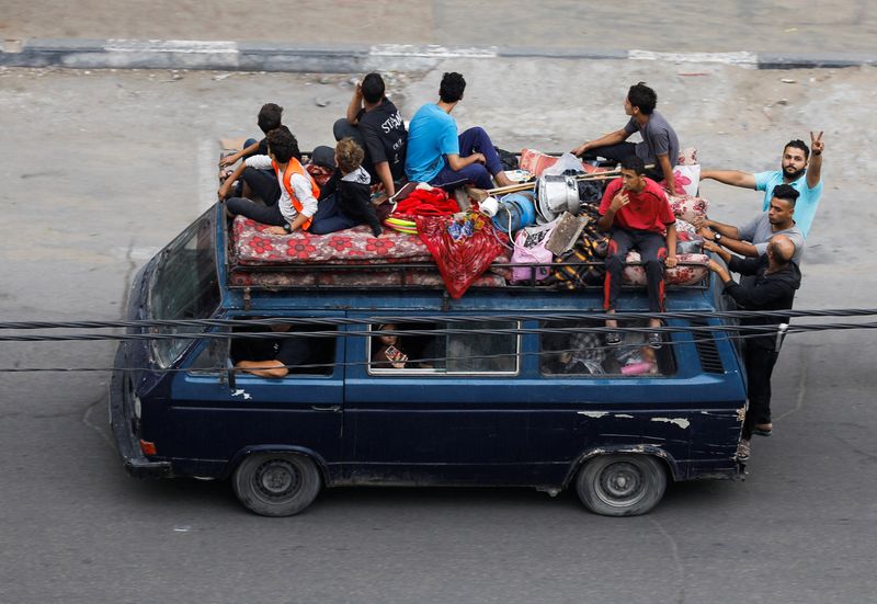 © Reuters. فلسطينيون يفرون من منازلهم بممتلكاتهم وسط غارات إسرائيلية في مدينة غزة يوم الجمعة. تصوير: صالح سليم - رويترز.

