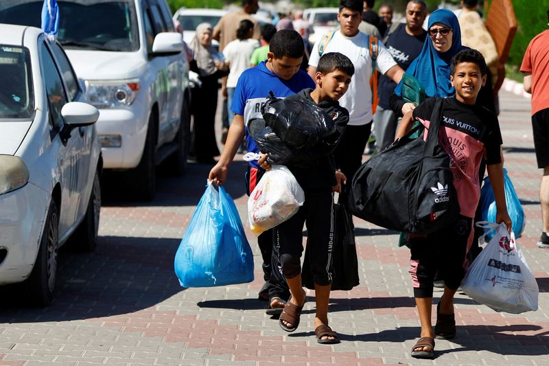 &copy; Reuters. Photo des familles de membres du personnel d'organisations internationales transportent leurs affaires pour se réfugier dans un centre des Nations Unies après que l'UNRWA a annoncé avoir transféré son centre d'opérations central au sud de la bande d
