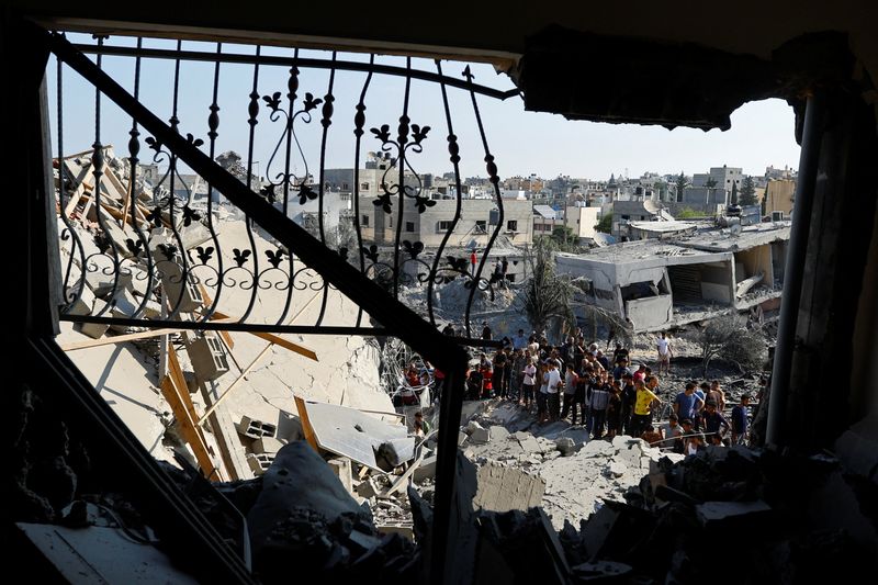 &copy; Reuters. فلسطينيون يتجمعون بالقرب من الحطام في أعقاب قصف صاروخي على مدينة خان يونس جنوب قطاع غزة يوم الأحد. تصوير: إبراهيم أبو مصطفى - رويترز.