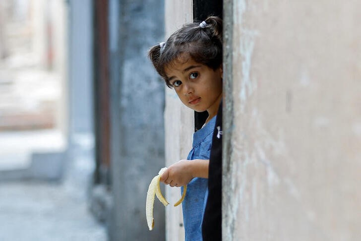 &copy; Reuters. Una niña palestina se asoma a la puerta de la casa de su familia en el campo de refugiados de Jan Yunis, en el sur de la Franja de Gaza. 14 octubre 2023. REUTERS/Ibraheem Abu Mustafa