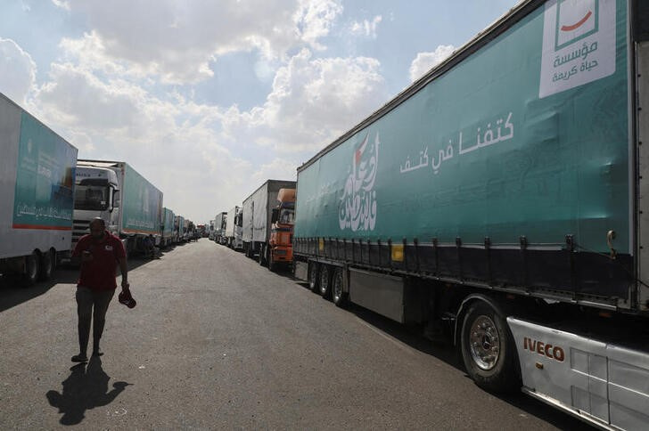 &copy; Reuters. Un hombre camina junto a camiones con ayuda humanitaria para los palestinos retenida en una carretera egipcia en camino a al paso fronterizo de Rafah con Gaza. 14 octubre 2023. REUTERS/Amr Abdallah Dalsh