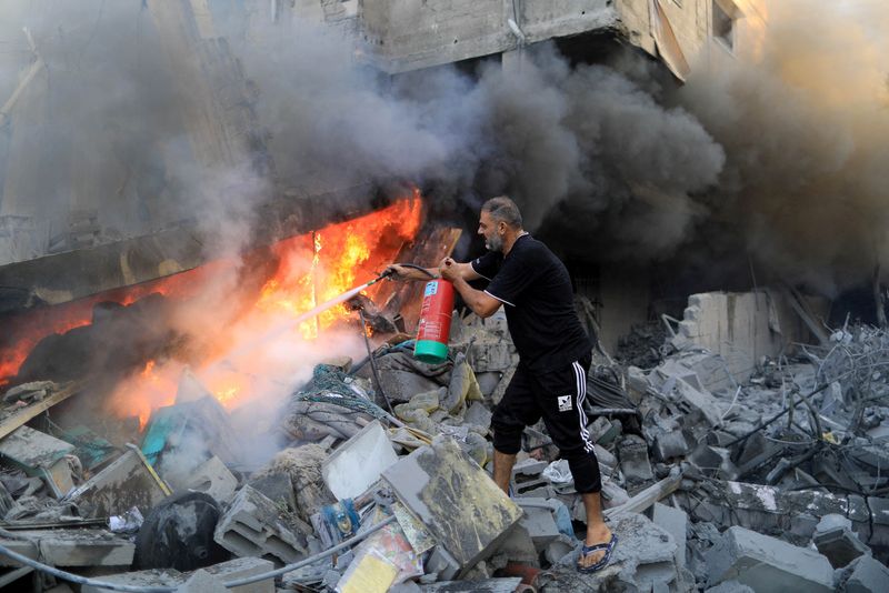 &copy; Reuters. رجل فلسطيني يطفئ حريق وسط أنقاض منزل عقب غارات إسرائيلية في خان يونس بجنوب قطاع غزة يوم الجمعة. تصوير: ياسر قديح - رويترز.
