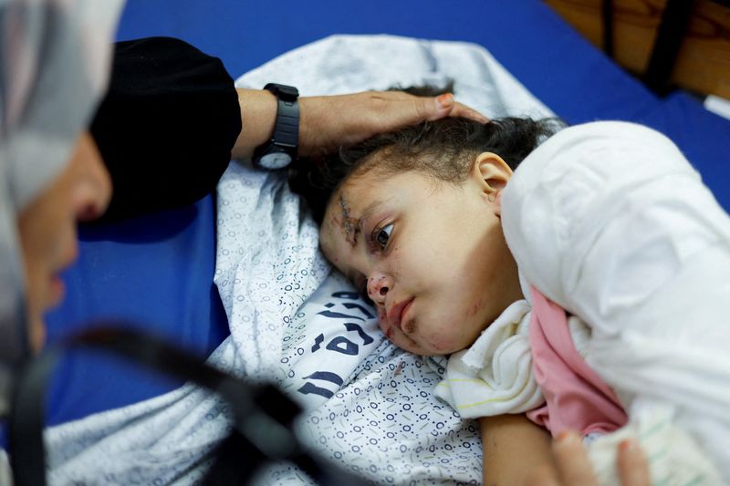 © Reuters. Palestinian girl Fulla Al-Laham, 4, who was wounded in an Israeli strike that killed 14 family members, including her parents and all her siblings, lies on a bed as her grandmother sits next to her, at a hospital in Khan Younis in the southern Gaza Strip, October 14, 2023. REUTERS/Mohammed Salem