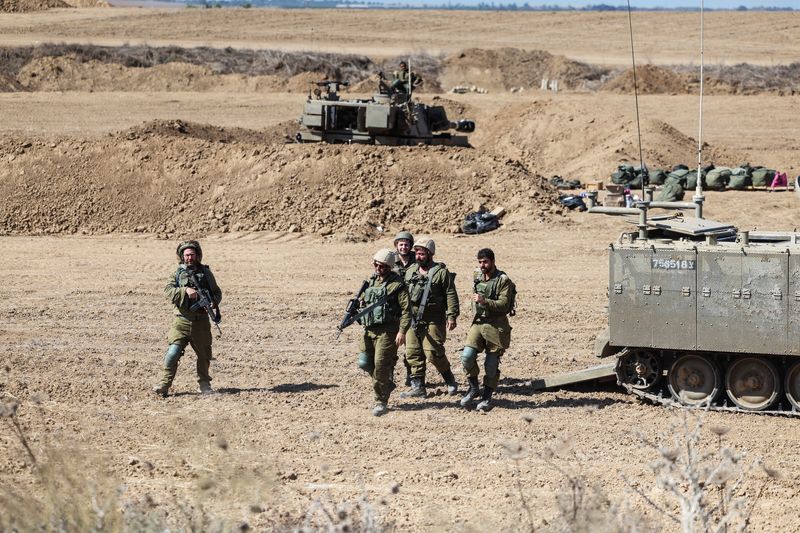 &copy; Reuters. Des soldats israéliens marchent à côté d’un véhicule militaire près de la frontière avec Gaza. /Photo prise le 15 octobre 2023/REUTERS/Ronen Zvulun