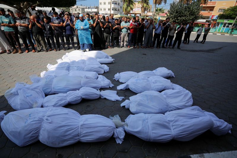 &copy; Reuters. فلسطينيون يصلون على عدد من جثامين الفلسطينيين عقب نقلهم من شاحنة للتبريد وسط اكتظاط مشارح المستشفيات في غزة بالجثث يوم الأحد جراء الضربات ا