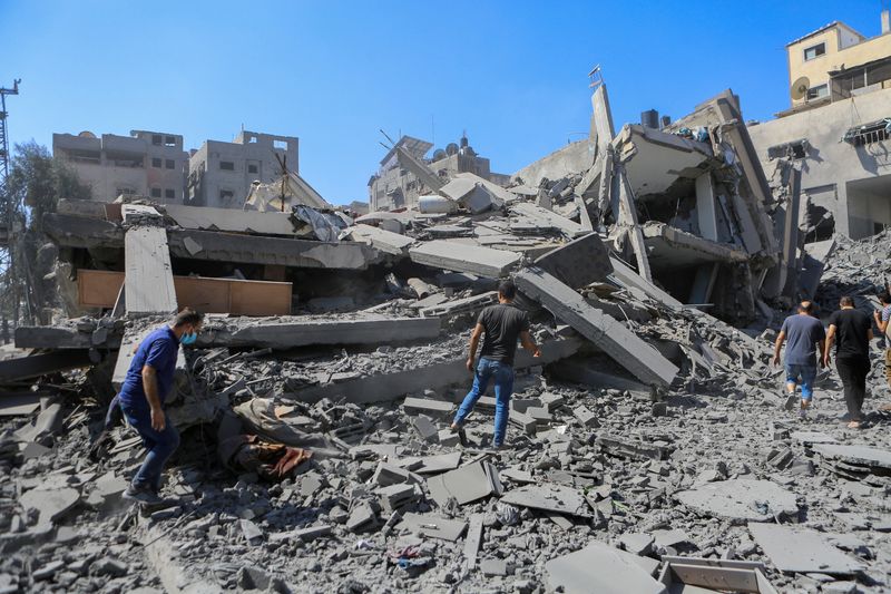 © Reuters. Palestinians walk past the rubble of houses following Israeli strikes in Gaza City October 15, 2023. REUTERS/Mutasem Murtaja