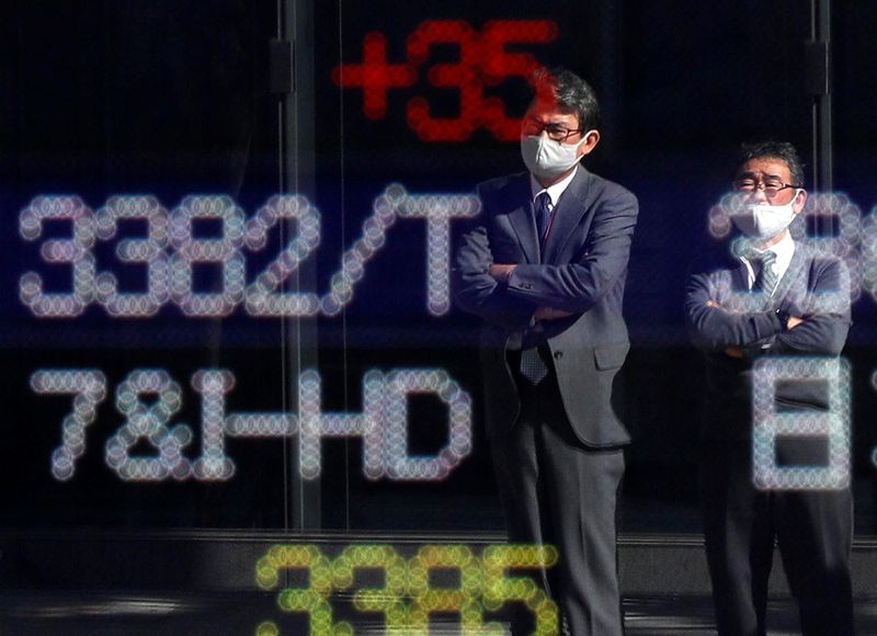 &copy; Reuters. Passersby wearing protective face masks are reflected on a stock quotation board outside a brokerage, amid the coronavirus disease (COVID-19) outbreak, in Tokyo, Japan November 10, 2020. REUTERS/Issei Kato/File photo