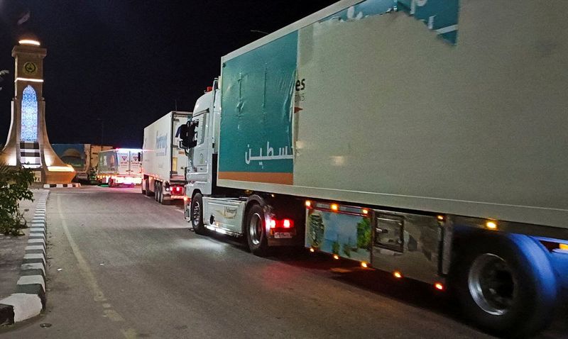 &copy; Reuters. １０月１７日、パレスチナ自治区ガザへの支援物資を積んだトラックがガザ南部とエジプトを結ぶラファ検問所に到着した。写真は１７日にエジプトからラファの検問所に向かうトラックの