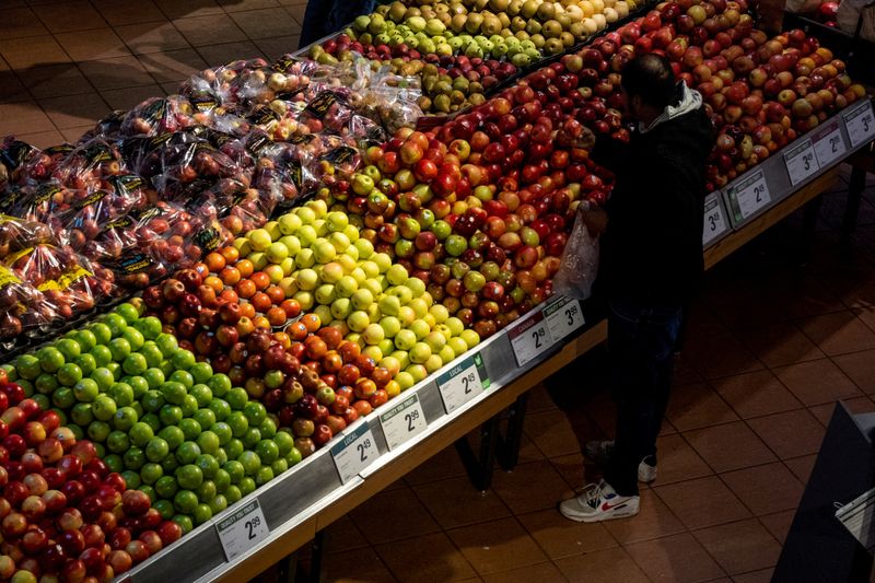 © Reuters. FILE PHOTO: A  man checks an apple while shopping at a grocery store in Toronto, Ontario, Canada November 22, 2022.  REUTERS/Carlos Osorio/File Photo