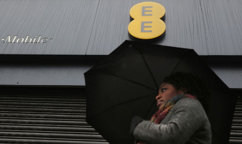&copy; Reuters. FILE PHOTO: A woman carries an umbrella past a closed EE shop in London February 5, 2015. REUTERS/Suzanne Plunkett/File photo