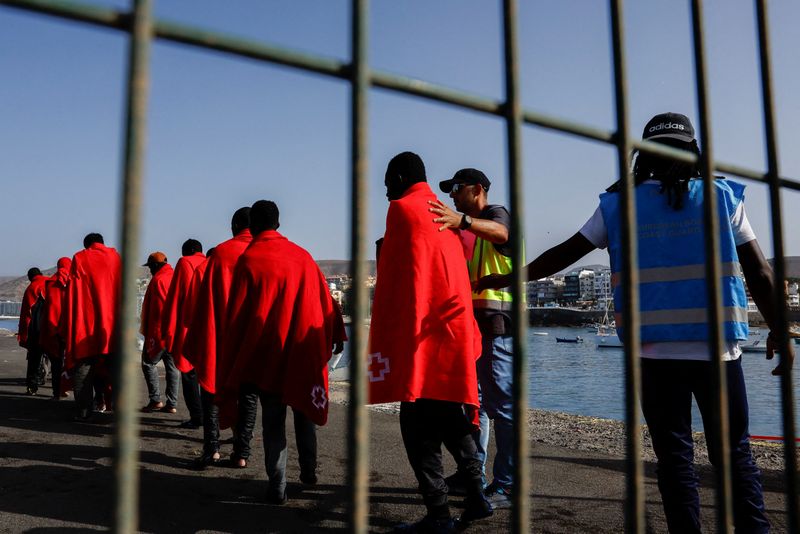 &copy; Reuters. La police Frontex accompagne plusieurs migrants vers une tente de la Croix-Rouge après avoir débarqué d'un navire des garde-côtes espagnols, dans le port d'Arguineguin, sur l'île de Grande Canarie, en Espagne. /Photo prise le 2 octobre 2023/REUTERS/B