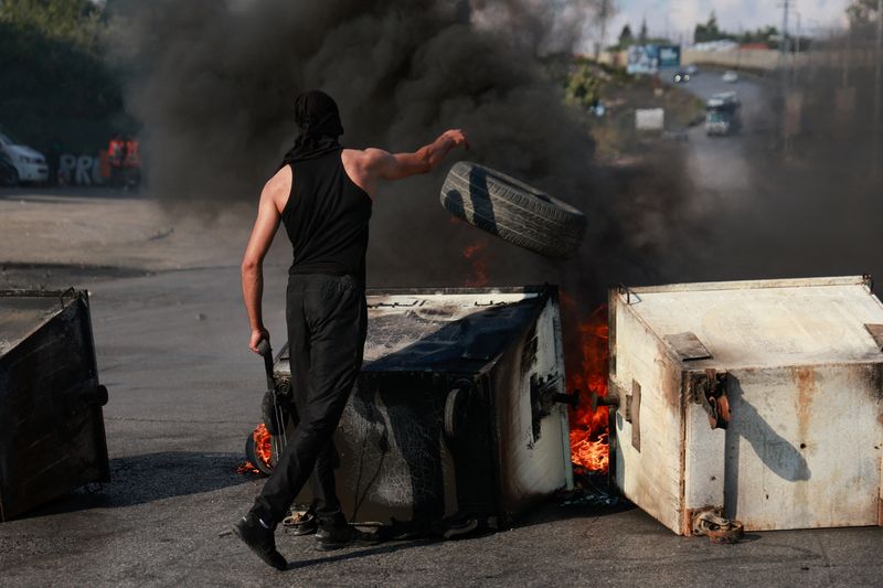 &copy; Reuters. Un palestino arroja un neumático al fuego durante los enfrentamientos con las fuerzas israelíes cerca de Ramala, en Cisjordania

Oct 18, 2023. REUTERS/Ammar Awad