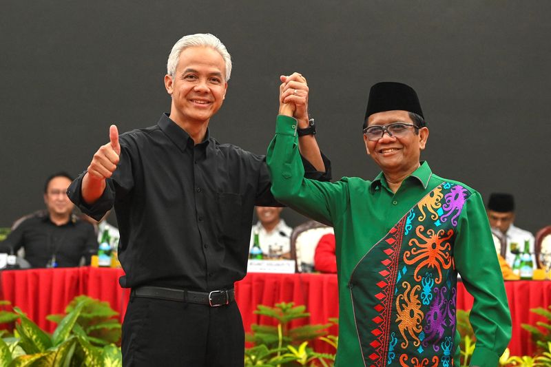 &copy; Reuters. Ganjar Pranowo, presidential candidate of the ruling Indonesian Democratic Party-Struggle (PDI-P), holds hands with his running mate, Mohammad Mahfud Mahmodin, chief security minister, known as Mahfud MD, as they pose for photographs during their declarat