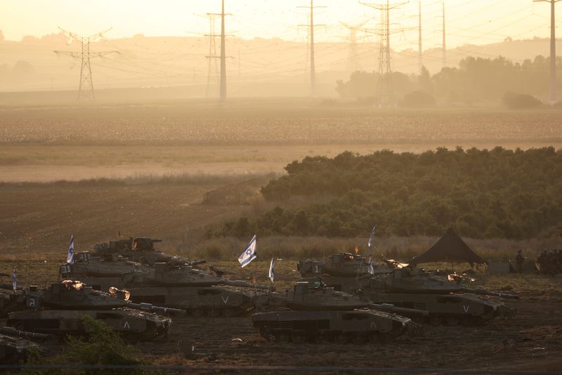 © Reuters. A formation of Israeli tanks and military personnel are positioned near Israel's border with the Gaza Strip, in southern Israel October 19, 2023. REUTERS/Violeta Santos Moura