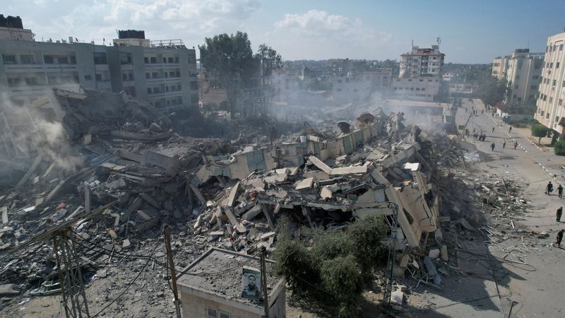 &copy; Reuters. فلسطينيون يتجمعون حول مبان سكنية دُمرت في ضربات جوية إسرائيلية في مدينة الزهراء جنوب مدينة غزة يوم الخميس في صورة لرويترز.
