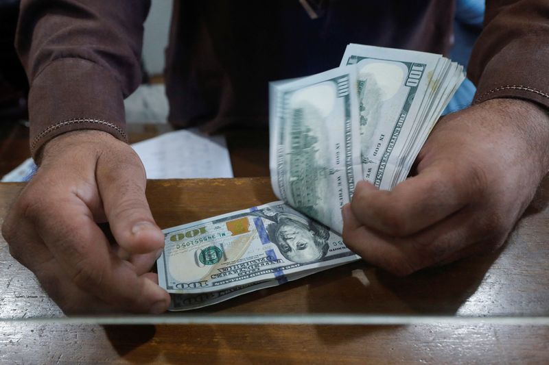 &copy; Reuters. Un dipendente di un banco di cambio conta le banconote in dollari statunitensi da dietro una cabina di vetro a Karachi, Pakistan, 7 settembre 2023.REUTERS/Akhtar Soomro
