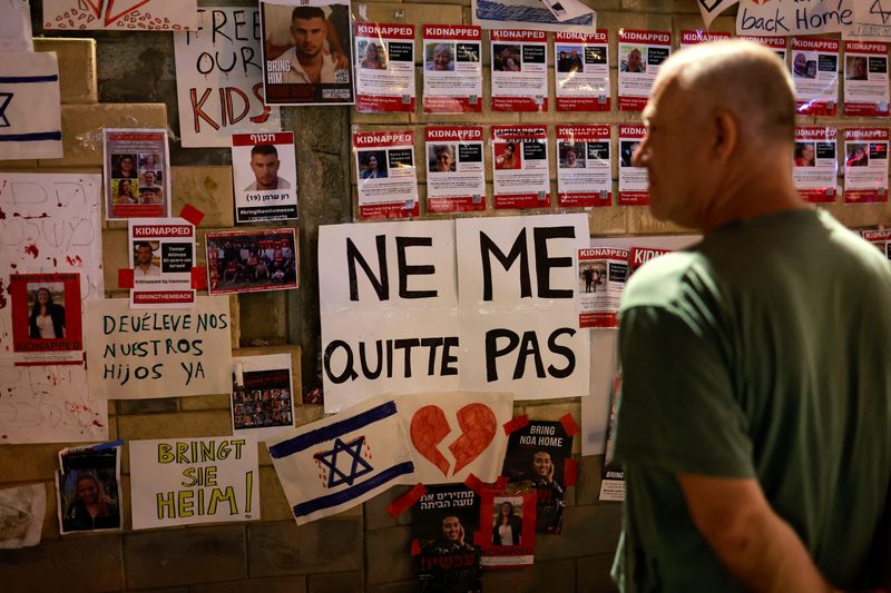 © Reuters. شخص ينظر إلى ملصقات تصور الرهائن والمفقودين في تل أبيب بإسرائيل يوم السبت. تصوير: عمار عوض - رويترز.