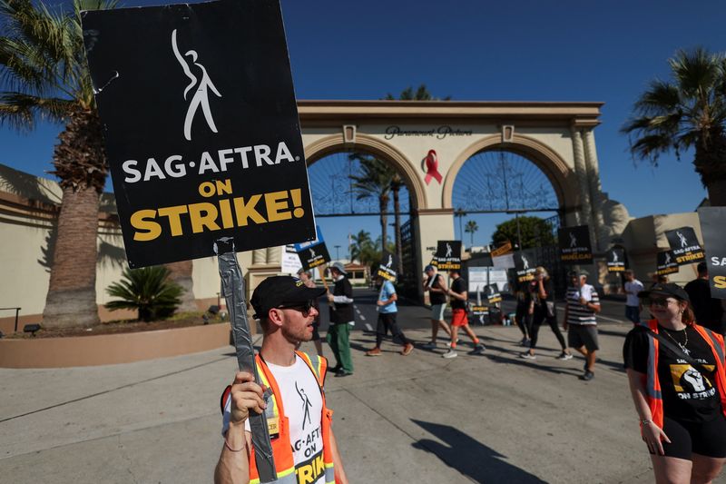 &copy; Reuters. Team captain Spencer Morgan holds a placard as he and other SAG-AFTRA members walk the picket line on the 100th day of their ongoing strike, outside Paramount Studios in Los Angeles, California, U.S., October 20, 2023. REUTERS/Mario Anzuoni