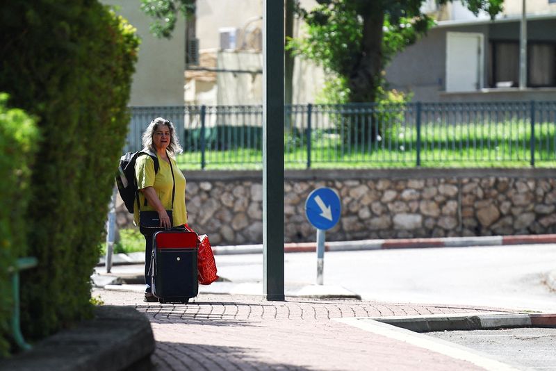 © Reuters. امرأة تقف مع أمتعتها قبل إجلائها من كريات شمونة بالقرب من الحدود الإسرائيلية مع لبنان في شمال إسرائيل يوم 20 أكتوبر تشرين الأول 2023. تصوير: ليسي نيسنر - رويترز.
