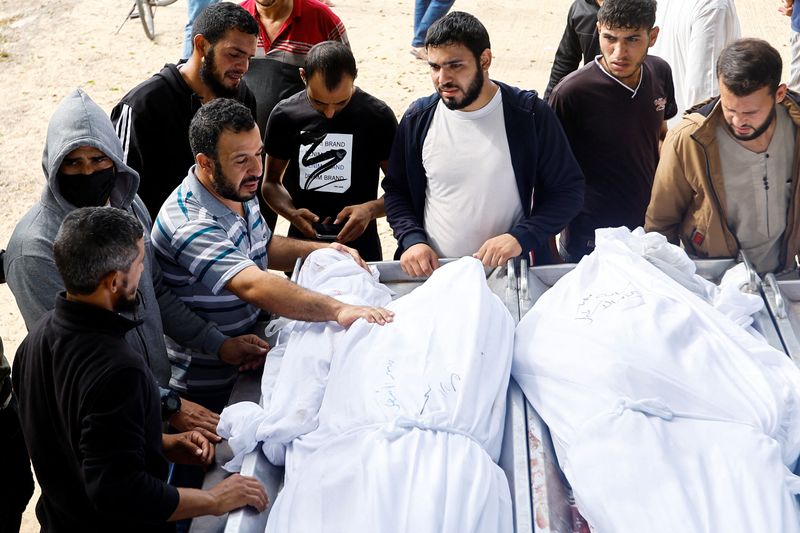 © Reuters. مشيعون يقفون بجانب الجثامين خلال جنازة فلسطينيين من عائلة الأسطل الذين قتلوا في غارات إسرائيلية بخان يونس في جنوب قطاع غزة يوم الأحد. تصوير: إبراهيم أبو مصطفى - رويترز.

