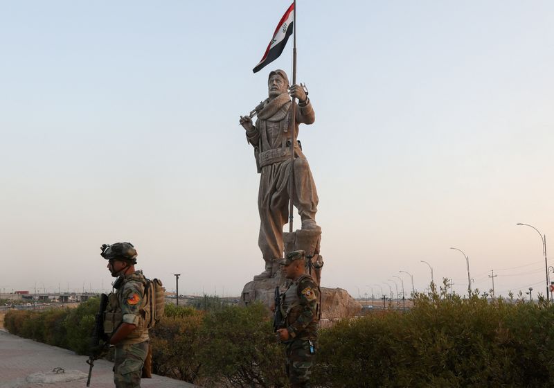 © Reuters. أحد عناصر قوات الأمن العراقية يحرس موقعا بجوار تمثال لأحد مقاتلي البشمركة الكردية في كركوك في الخامس من سبتمبر أيلول 2023 . تصوير : أكو رشيد - رويترز . 
