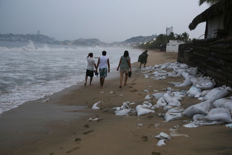 &copy; Reuters. Des gens marchent le long d’une plage alors que l’ouragan Otis se dirige vers Acapulco, au Mexique. /Photo prise le 24 octobre 2023/REUTERS/Javier Verdin