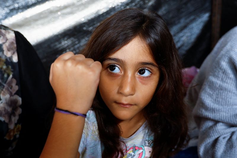 &copy; Reuters. Hija del palestino Ali Daba, que decidió junto a su mujer separar a sus hijos y marcarlos con pulseras para ayudar a identificarlos, por el temor a que mueran en ataques israelíes, muestra su pulsera en su refugio de Jan Yunis, en el sur de la Franja de