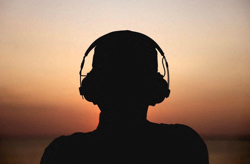 &copy; Reuters. FILE PHOTO: A man watches the sunset while wearing a headphone and listening to music, in Colombo, Sri Lanka February 23, 2023. REUTERS/Dinuka Liyanawatte/File Photo