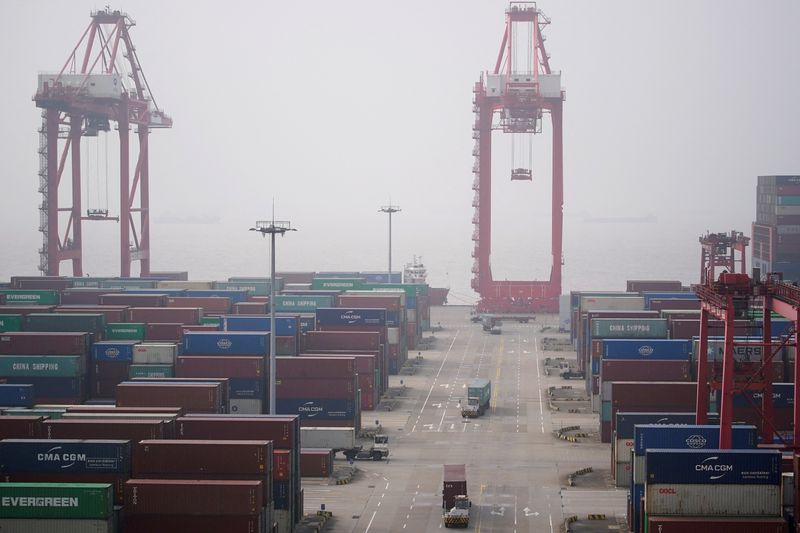 &copy; Reuters. FILE PHOTO: Trucks travel past containers at the Yangshan Deep Water Port in Shanghai, China January 13, 2022. Picture taken January 13, 2022. REUTERS/Aly Song/File Photo