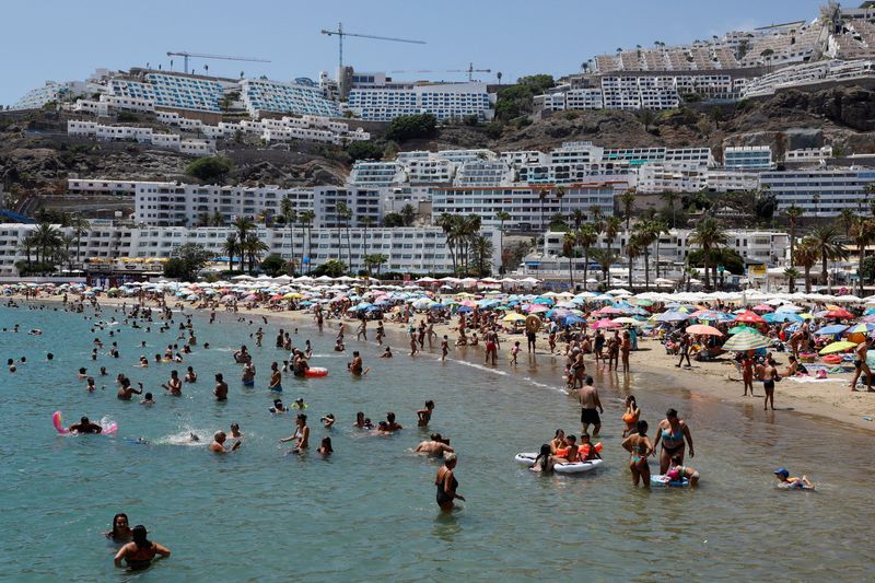 &copy; Reuters. FILE PHOTO: Tourists bathe and sunbathe on the beach of Puerto Rico in the south of the island of Gran Canaria, Spain, August 6, 2023. REUTERS/Borja Suarez/File Photo