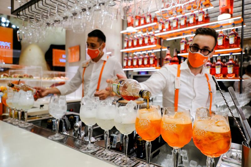 © Reuters. FILE PHOTO: Bartenders pour drinks at a Campari inauguration of a new brand house for Aperol, its best-selling beverage, in Venice. Italy, August 30, 2021. REUTERS/Manuel Silvestri/File Photo